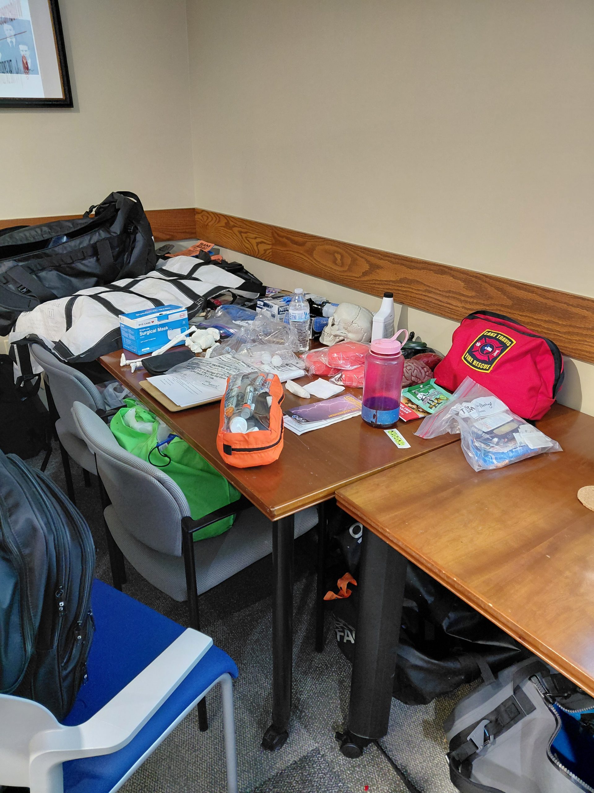 A table covered in wilderness first aid training supplies including EpiPens,<br />
surgical masks, a skull model, gloves, first aid kits, and a red Lake Travis Fire Rescue bag,<br />
used during the Expedition School course at UT Austin.