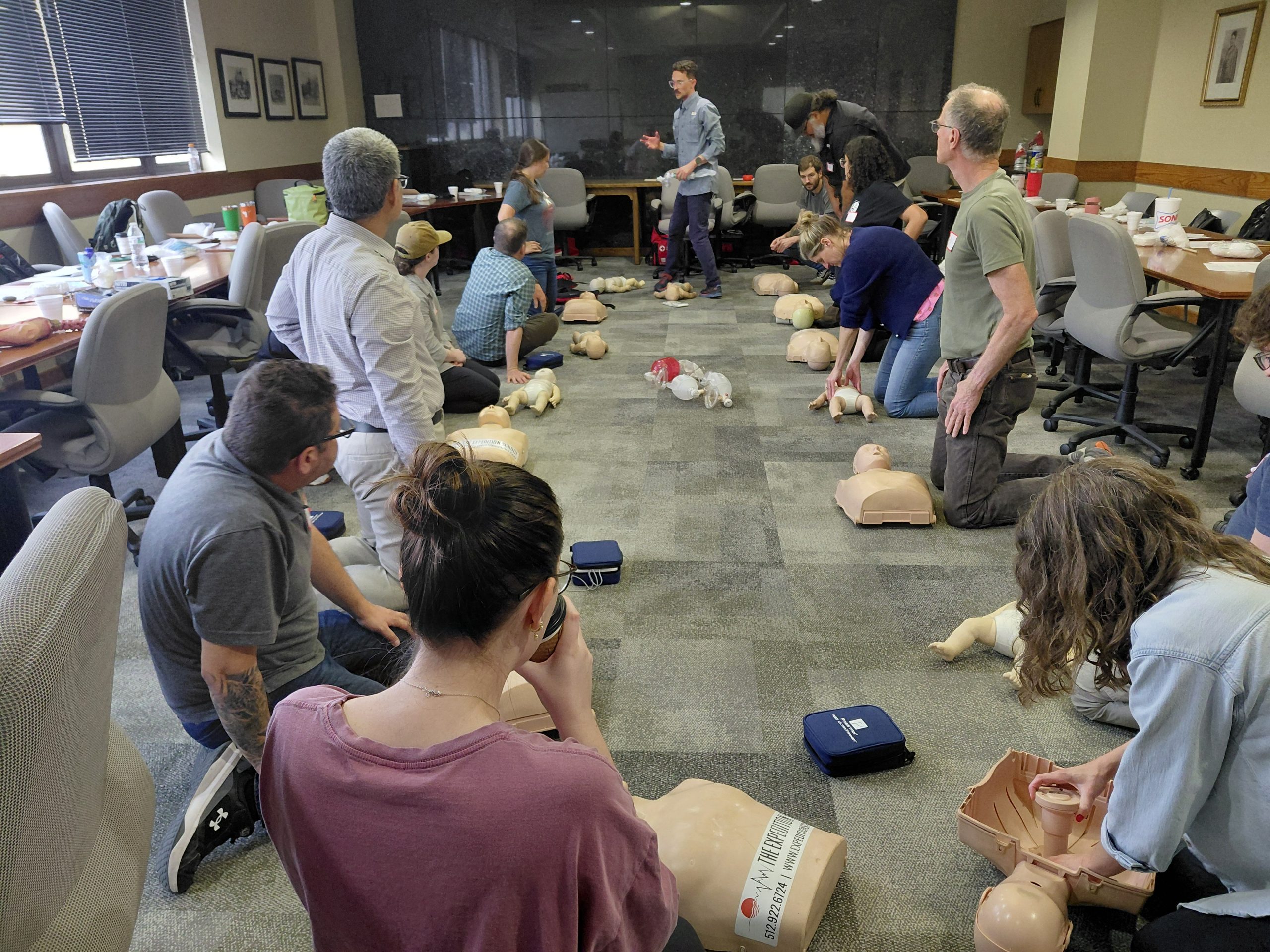 Wide angle shot of the entire class on the floor performing CPR chest<br />
compressions on training mannequins during the hands-on session of the Expedition School<br />
Wilderness First Aid course, with instructor Adam Shedlosky standing in the center.